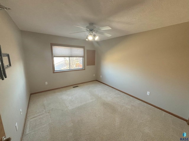 spare room featuring ceiling fan, carpet floors, and a textured ceiling