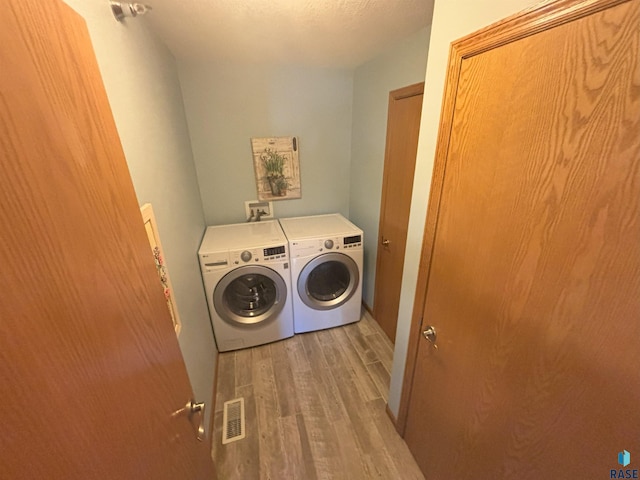 washroom featuring hardwood / wood-style floors, independent washer and dryer, and a textured ceiling