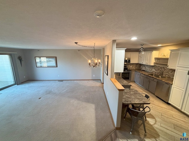 kitchen featuring backsplash, sink, decorative light fixtures, white cabinetry, and stainless steel appliances