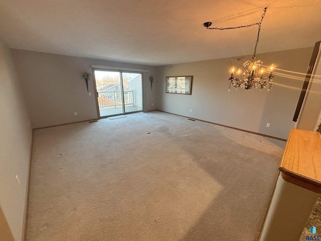 carpeted spare room featuring an inviting chandelier