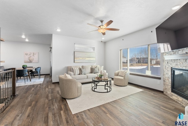 living room with plenty of natural light, ceiling fan, a fireplace, and dark hardwood / wood-style floors