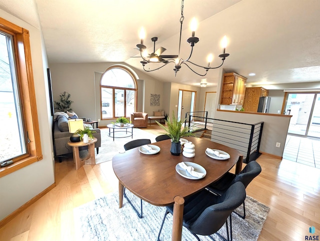 dining area with plenty of natural light, vaulted ceiling, light hardwood / wood-style flooring, and an inviting chandelier