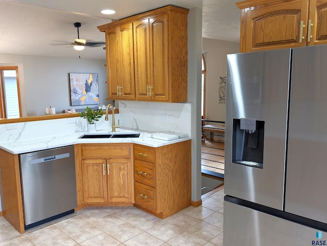 kitchen featuring light stone countertops, appliances with stainless steel finishes, ceiling fan, and sink