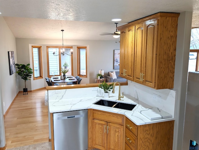 kitchen with ceiling fan with notable chandelier, sink, hanging light fixtures, stainless steel dishwasher, and light wood-type flooring