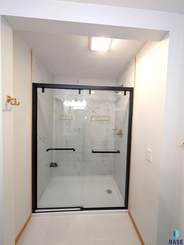 bathroom with tile patterned floors, a shower with shower door, and a textured ceiling