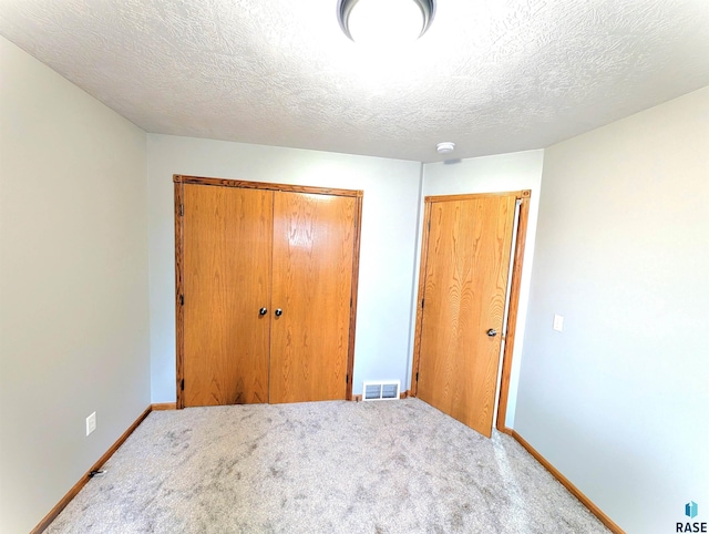 unfurnished bedroom with a textured ceiling, carpet floors, and a closet