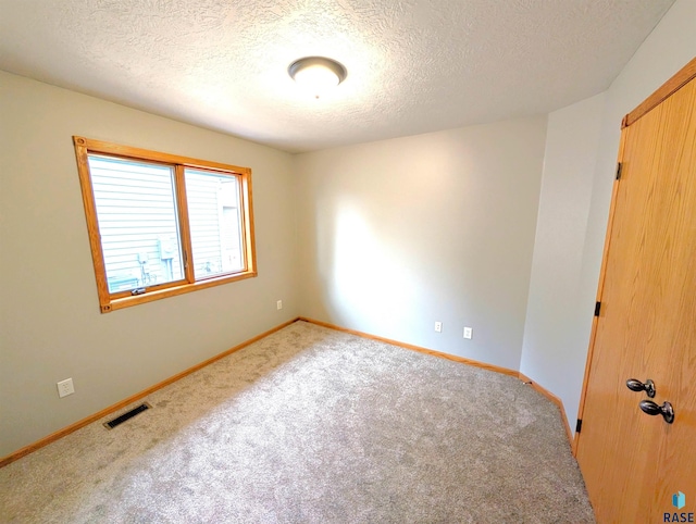 empty room featuring light carpet and a textured ceiling