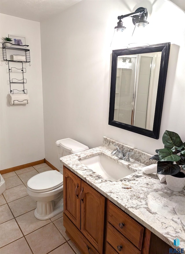 bathroom with tile patterned flooring, vanity, toilet, and an enclosed shower