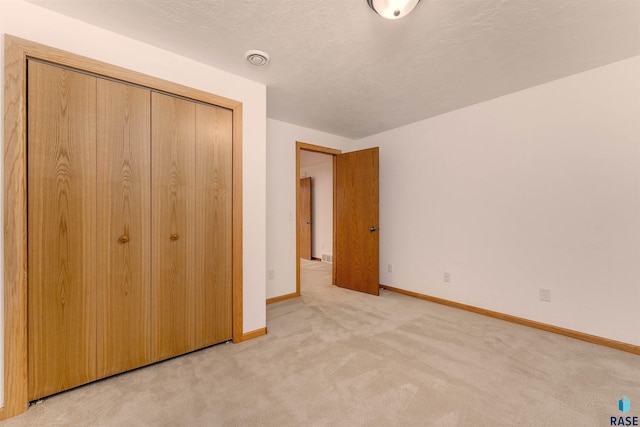 unfurnished bedroom with light carpet and a closet