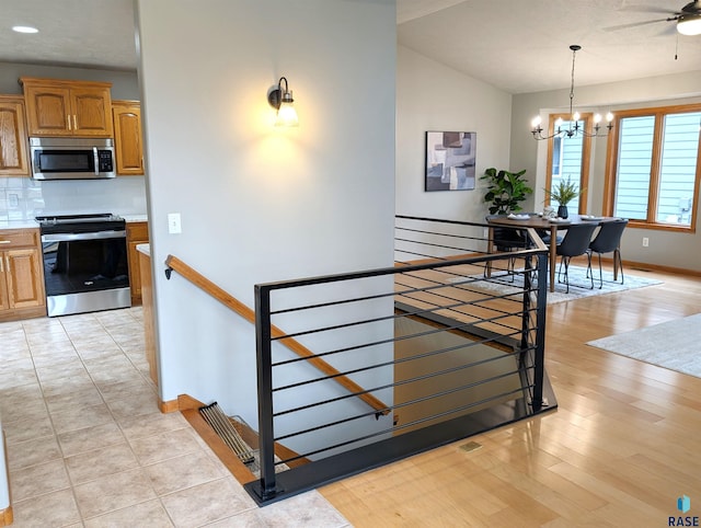 staircase with vaulted ceiling and ceiling fan with notable chandelier