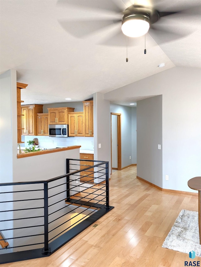 kitchen with kitchen peninsula, vaulted ceiling, and light wood-type flooring