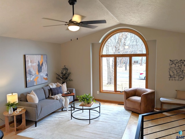 living room with a textured ceiling, light hardwood / wood-style floors, ceiling fan, and lofted ceiling