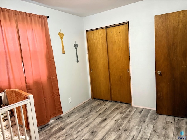 unfurnished bedroom with a crib, hardwood / wood-style floors, and a closet