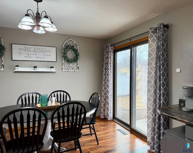 dining area with hardwood / wood-style flooring and an inviting chandelier