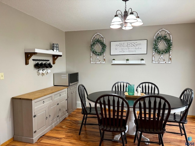 dining area with light hardwood / wood-style floors, a textured ceiling, and an inviting chandelier