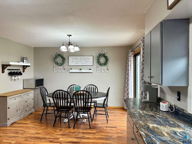 dining space featuring a chandelier, a textured ceiling, and light hardwood / wood-style floors