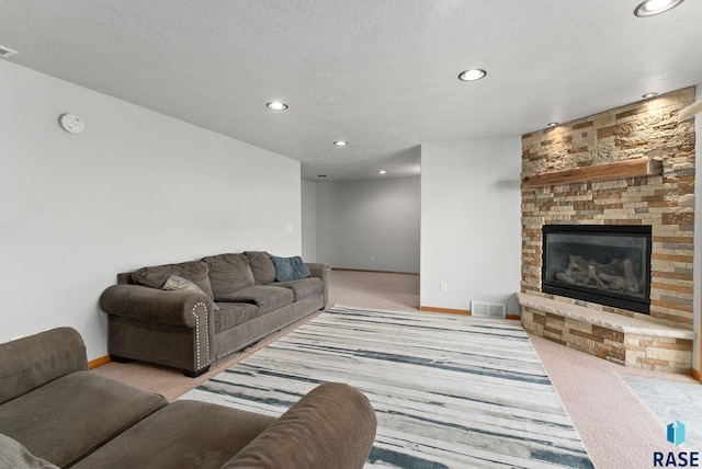 living room with a fireplace, light colored carpet, and a textured ceiling