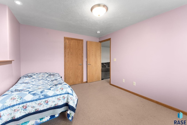 bedroom featuring light colored carpet and a textured ceiling