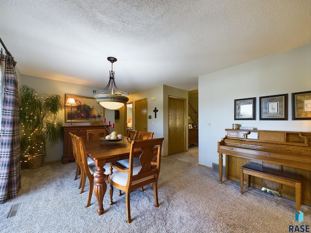 dining room with light colored carpet and a textured ceiling