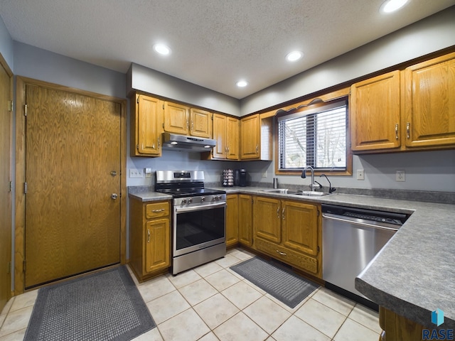 kitchen with sink, light tile patterned flooring, stainless steel appliances, and a textured ceiling