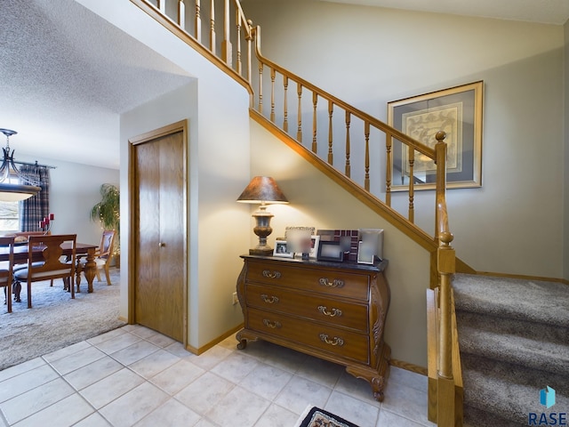 staircase with a textured ceiling and tile patterned floors