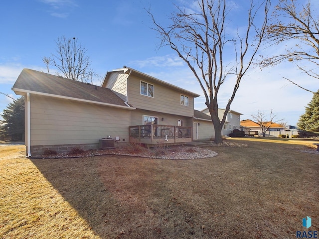 back of property with a wooden deck, a yard, and central AC