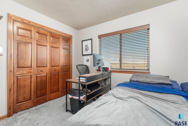 bedroom with a textured ceiling, light colored carpet, and a closet