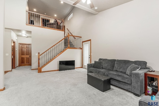 carpeted living room with ceiling fan and a high ceiling