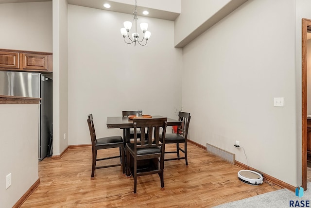 dining area featuring light hardwood / wood-style floors and an inviting chandelier