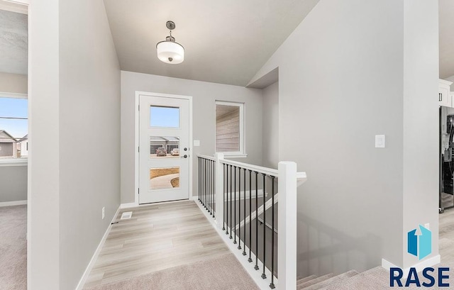 hallway with light hardwood / wood-style floors and lofted ceiling