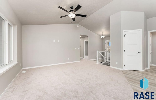 interior space with ceiling fan, light colored carpet, and vaulted ceiling