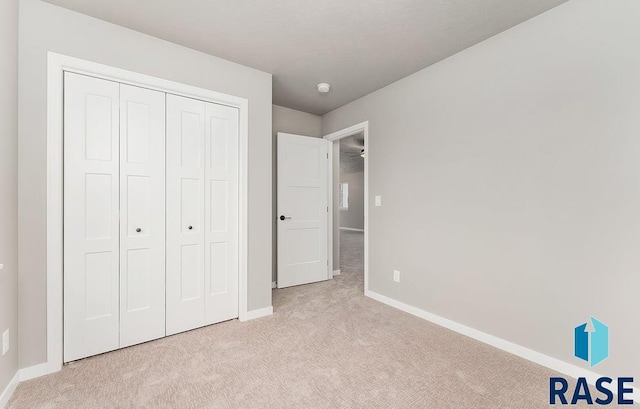 unfurnished bedroom featuring light carpet and a closet