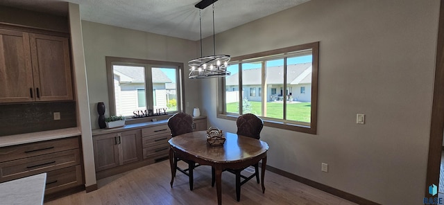 dining room featuring a wealth of natural light, a chandelier, a textured ceiling, and light hardwood / wood-style floors