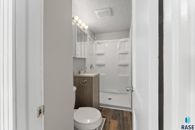 bathroom with vanity, a textured ceiling, a shower, hardwood / wood-style flooring, and toilet