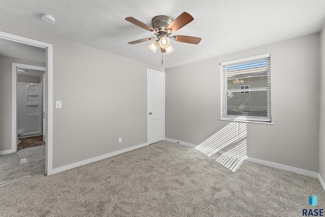 carpeted empty room featuring ceiling fan and a textured ceiling