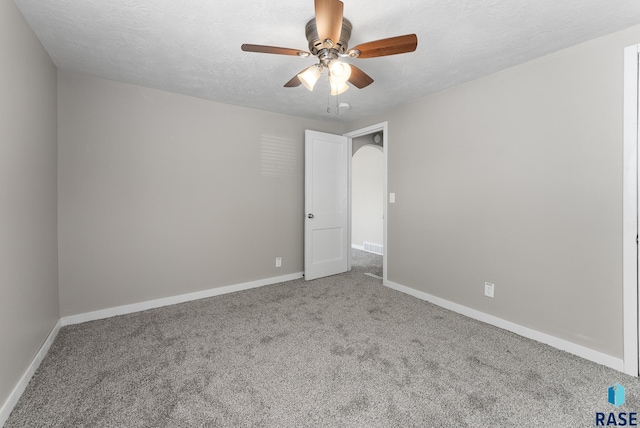 carpeted spare room with a textured ceiling and ceiling fan