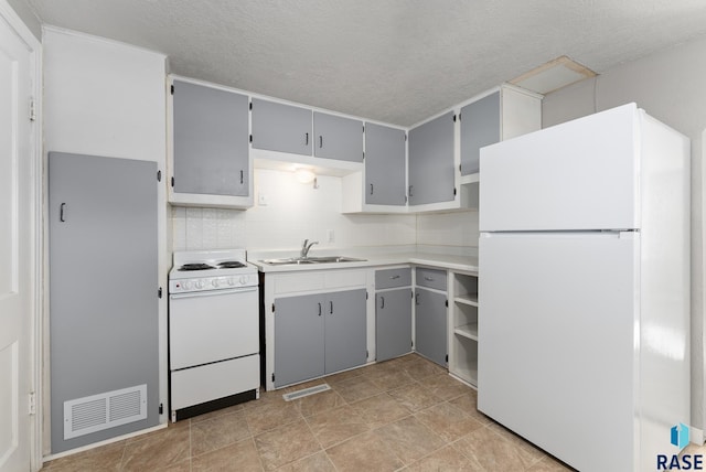 kitchen featuring a textured ceiling, gray cabinets, sink, and white appliances