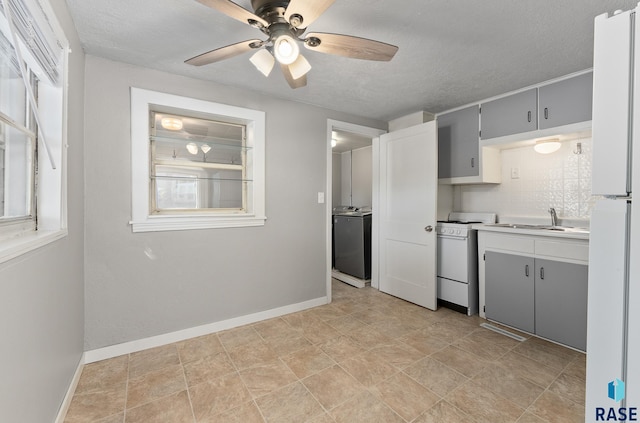 kitchen featuring white appliances, washer / clothes dryer, a healthy amount of sunlight, and gray cabinetry