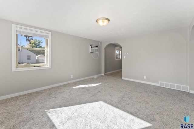 carpeted empty room featuring an AC wall unit