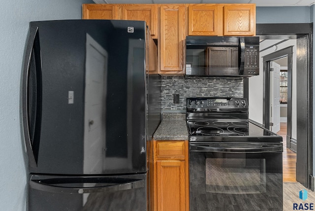 kitchen featuring wood-type flooring, backsplash, and black appliances