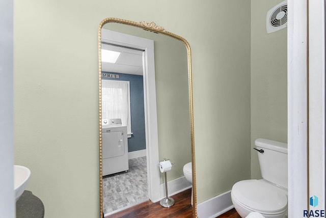 bathroom featuring washer / clothes dryer, hardwood / wood-style flooring, and toilet