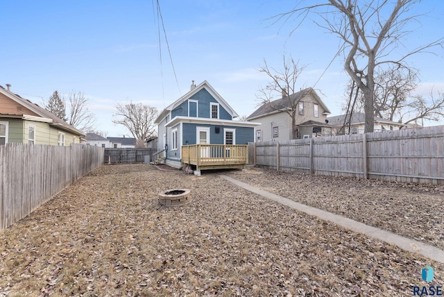 rear view of property with a deck and an outdoor fire pit