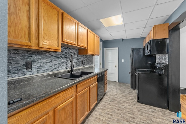 kitchen with sink, dark stone counters, a paneled ceiling, decorative backsplash, and black appliances