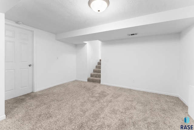 basement featuring carpet flooring and a textured ceiling