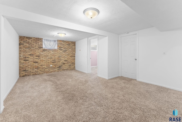 basement featuring carpet flooring, brick wall, and a textured ceiling