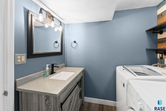 interior space featuring washer and clothes dryer, vanity, hardwood / wood-style floors, and a textured ceiling