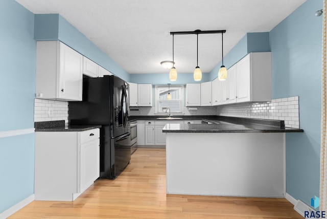 kitchen with kitchen peninsula, decorative backsplash, sink, decorative light fixtures, and white cabinetry