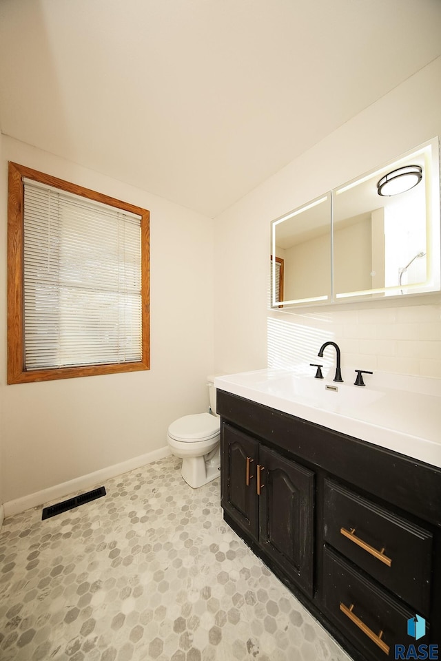 bathroom featuring tasteful backsplash, vanity, and toilet