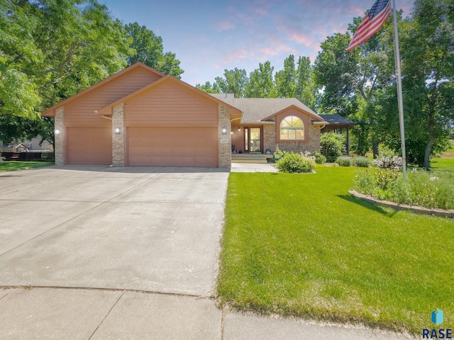 ranch-style home featuring a lawn and a garage