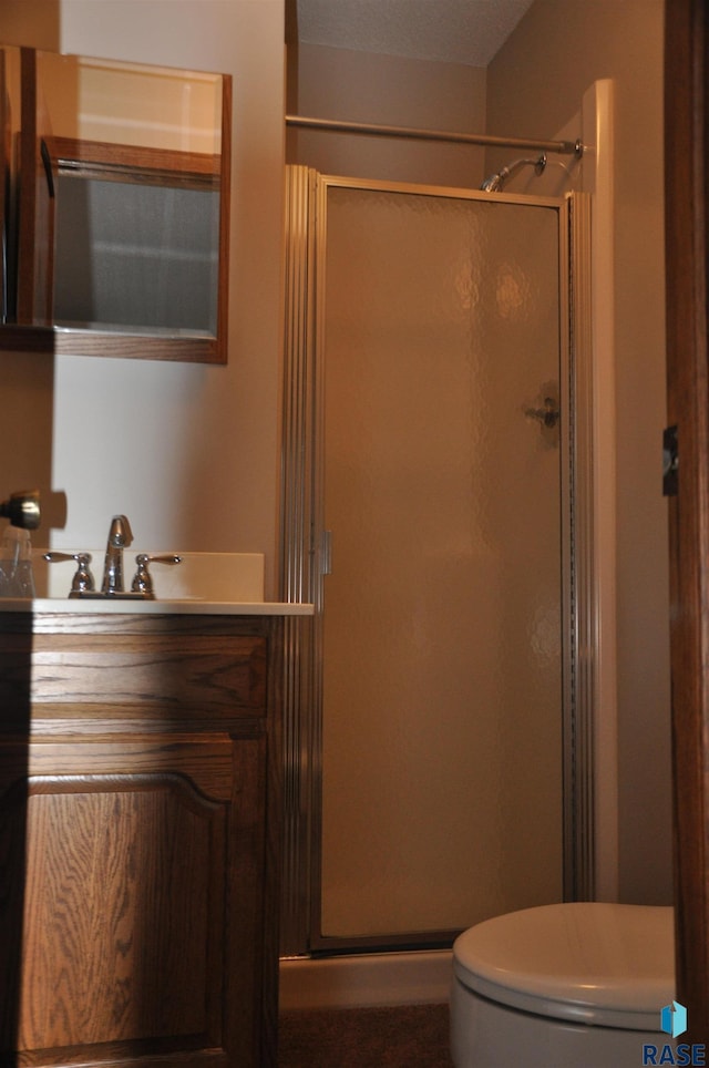 bathroom featuring vanity, toilet, and a shower with shower door